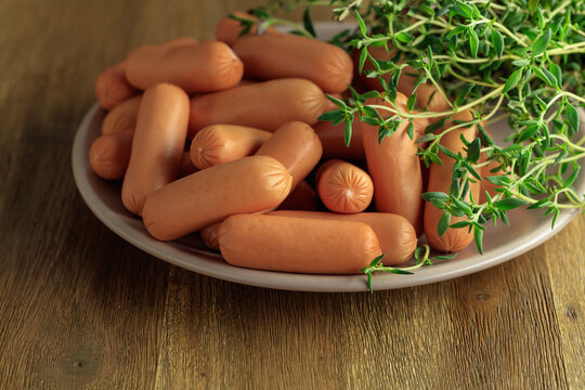 Boiled sausages with thyme on a wooden table.
