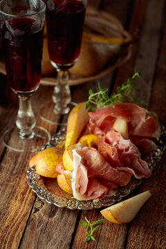 Prosciutto with pears and thyme on a silver tray.