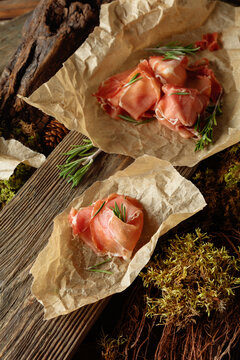 Prosciutto slices with rosemary wrapped in paper.