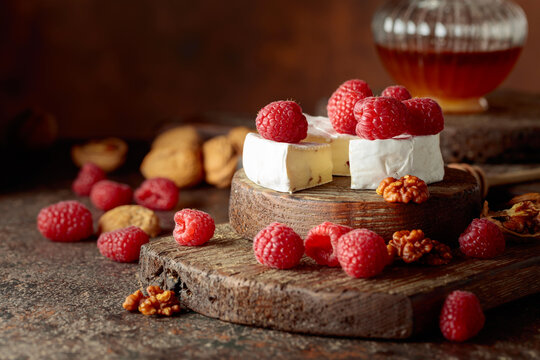 Camembert cheese with fresh raspberries, honey, and walnuts.