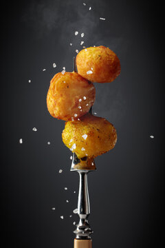 Roasted potatoes on a fork sprinkled with sea salt.