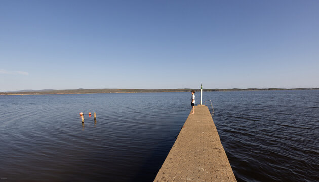 teenage boy on pier overlooking Grotto Lagoon, Hermanus, South Africa