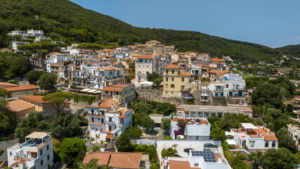 Fototapeta premium Panoramic aerial view of San Felice Circeo historic village nestled on a green hillside with traditional white buildings and orange rooftops under a bright sunny sky in Lazio, Italy.