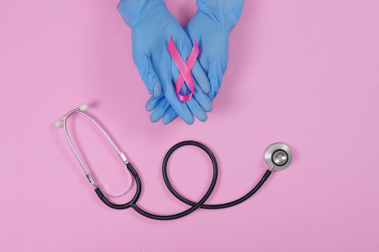 Medical worker hands holding pink ribbon with stethoscope for breast cancer awareness