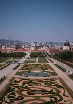 Veduta aerea e panoramica dei giardini barocchi del Palazzo del Belvedere con fontana e geometrici ricami di siepi, con lo sfondo del Belvedere Inferiore e lo skyline della citt&agrave; di Vienna, Austria.