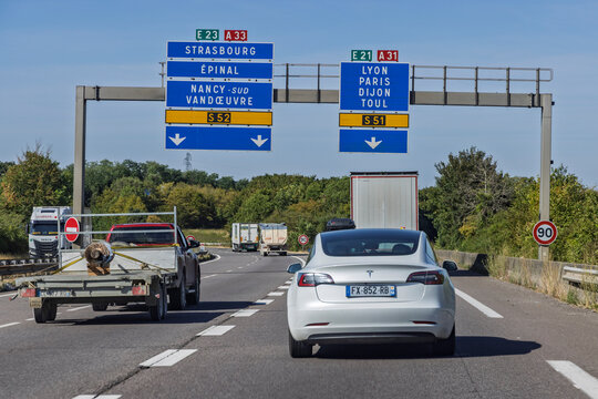 Nancy, France - 24 July 2026: White Tesla Model 3 driving on A31 motorway under overhead directional signs for Lyon, Paris, and Strasbourg.
