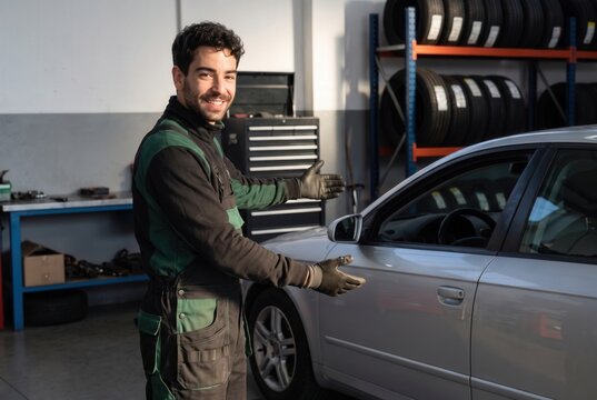 Male mechanic standing in garage, inviting customers for car maintenance and repair