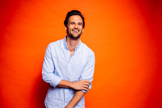 Cheerful handsome man standing against orange background