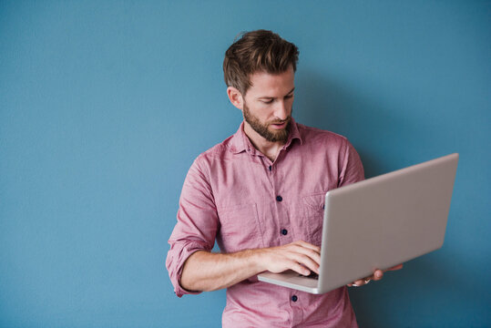 Man using laptop against blue wall