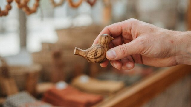 Hand holding wooden bird figurine with figurine blurred background background workshop holding carved