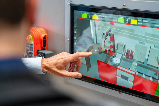 Man points at a touchscreen displaying an industrial robot