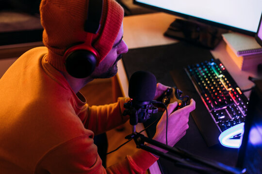 Gaming influencer wearing wireless headphones and playing video games at home