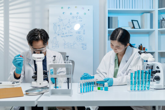 Scientists perform laboratory experiments using microscopes, pipettes and test tubes while analyzing samples in modern research laboratory, representing biotechnology, diagnostics and medical science.
