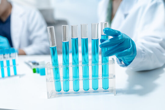 Scientists analyze liquid samples using test tubes, microscopes, and laboratory equipment, representing biotechnology, medical diagnostics, research, and healthcare innovation.