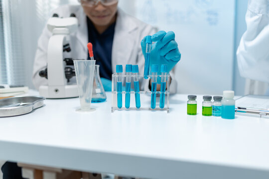 Scientists analyze liquid samples using test tubes, microscopes, and laboratory equipment, representing biotechnology, medical diagnostics, research, and healthcare innovation.