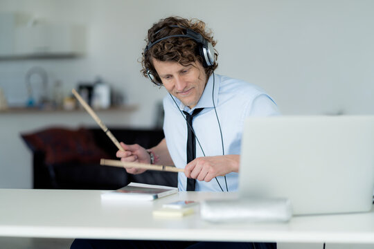 Businessman wearing headphones and drumming on his desk