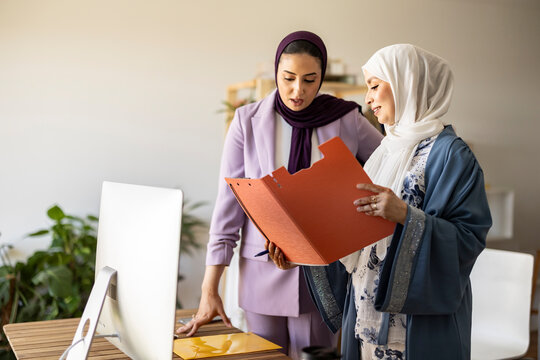 Happy wedding planner discussing over document with colleague