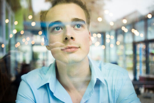 Daydreaming young man behind windowpane