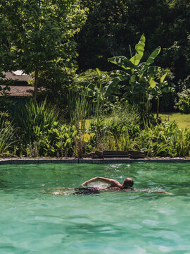 Swimmer exercising freestyle in a lush green garden pool