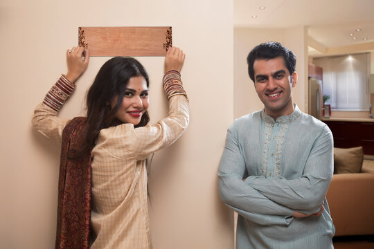 Newlywed couple in traditional dress placing name plate to home