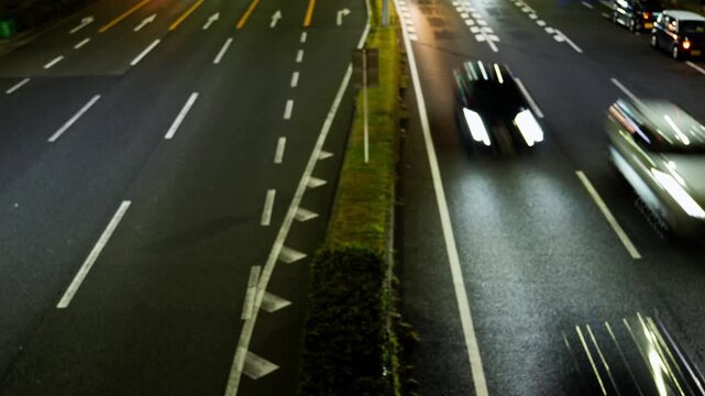 歩道橋から見下ろす夜間の幹線道路と車のライトが描くタイムラプス風の光跡