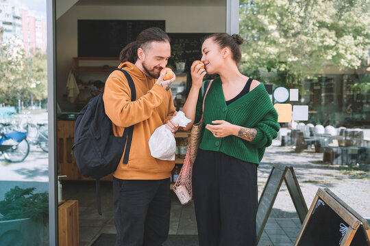 Couple smelling apples standing outside zero waste shop