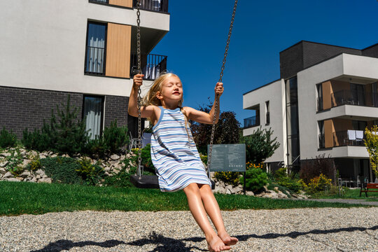 A carefree girl enjoys swinging in a modern courtyard on a summer day