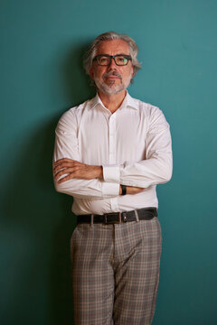 Mature male professional standing with arms crossed over green background