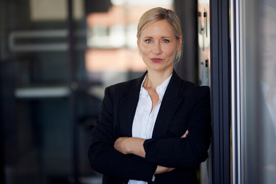 Confident businesswoman with arms crossed standing in modern office