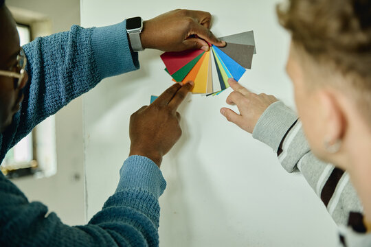 African American man and Caucasian man choosing wall paint colors from palette during house renovation. Image suitable for interior design services and home improvement marketing