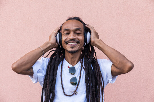 Portrait of mature man with dreadlocks and headphones, listening music with closed eyes