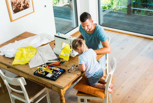 Father and daughter at home using sewing machine