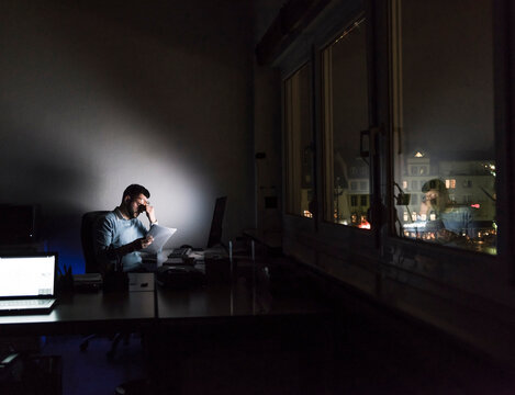 Exhausted businessman sitting at desk in his office by night