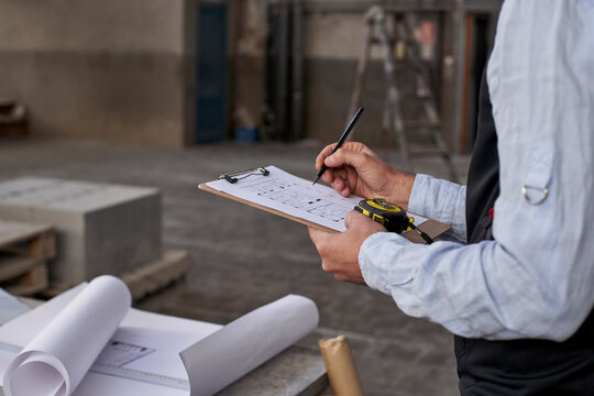 Close-up of male architect writing on document while standing in building