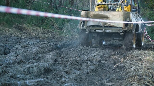 Extreme off roading competition. Low angle view shows powerful 4x4 vehicle spinning tires, kicking up wet mud and steam. Action packed and adventurous motorsport scene on rugged, dirty track