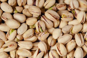 Fototapeta premium background of Pistachios filling the frame, showing cracked shells and vibrant green nuts, offering a delicious and healthy snack