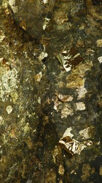 Vertical abstract natural background of rough rock texture with shimmering gold leaf, Gold foil mineral flakes, ideal for earthy, organic, luxury and textured design use.