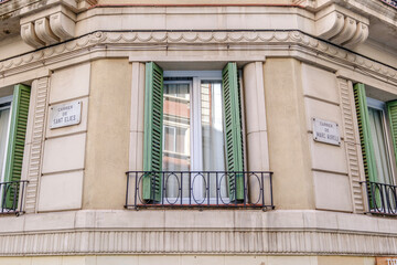Obraz premium Traditional Barcelona Building Facade Corner with Green Shutters and Street Signs, Classic Architecture