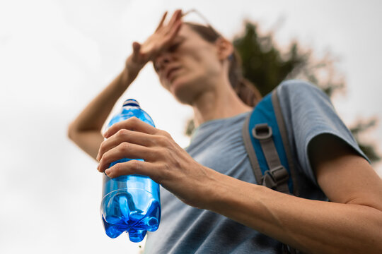 Woman Suffering From Heat Stress Holding Water Bottle During Summer Heatwave
