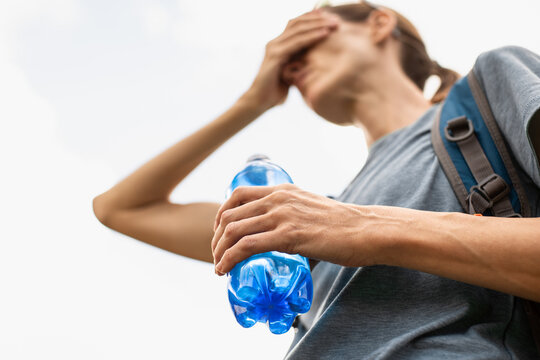 Exhausted Woman Holding Water Bottle During extream Summer Heat With Dehydration And Heat Stress Concept
