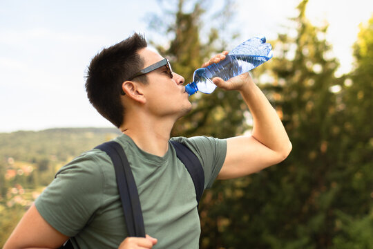 Young Man Drinking Water During Summer Hike to Stay Hydrated in Hot Weather
