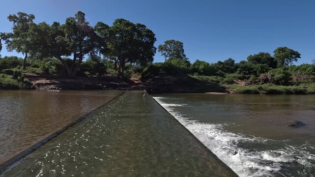 Shingwedzi River flows over low level weir bridge with heron and croc