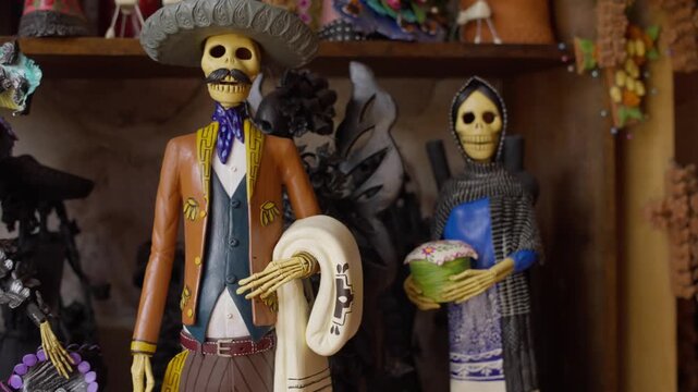 Colorful handmade Catrina sculptures displayed on artisan workshop shelf, painted with beautiful subtle colors