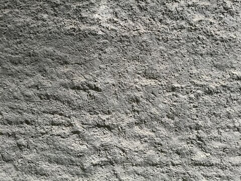 Close-up of rough grey concrete texture with shadows and highlights