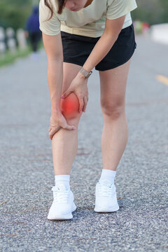Young adult female runner with knee pain from ACL injury or patellofemoral syndrome. woman having joint ache, ligament tear or patellar tendinitis during running. Sports medical and healthcare concept