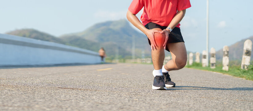 Young adult male runner with knee pain from ACL injury or patellofemoral syndrome. Man having joint ache, ligament tear or patellar tendinitis during running. Sports medical and healthcare concept