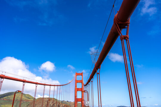 Golden Gate Bridge pedestrian walkway with red cables and blue sky