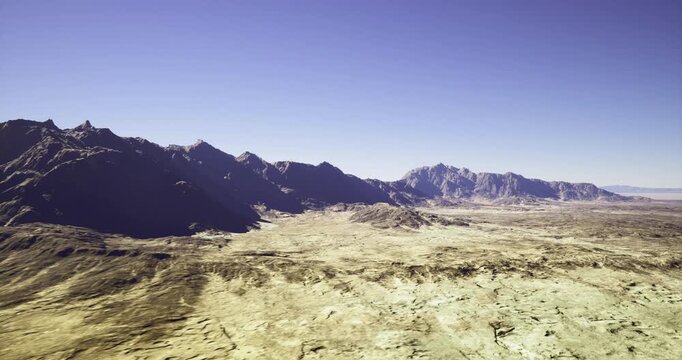 wide sandstone expanse under clear sky, sunbaked surface with cracked patterns and distant serrated ridgelines, minimal vegetation and crisp light ideal