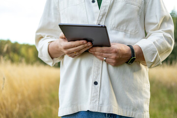 Farm manager holds tablet standing in golden wheat field. Concept of data-driven decision making in sustainable agriculture. © Ina