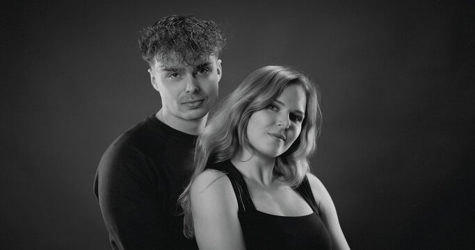 Man and woman posing intimately, looking at camera in a studio